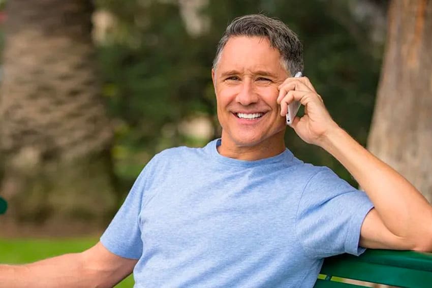 man sitting on park bench, taking on phone