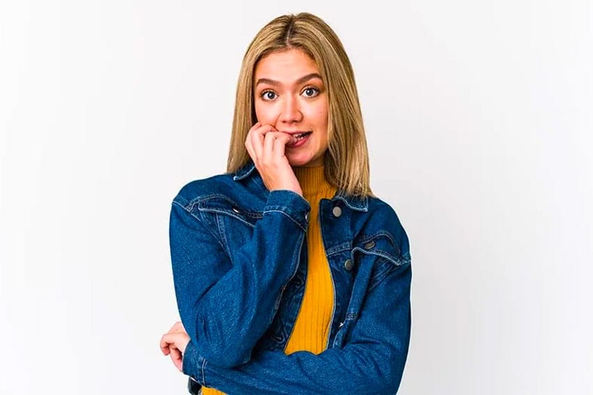 woman in jean jacket biting her nails