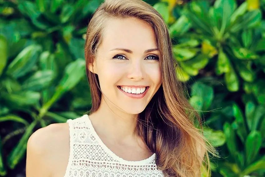 woman standing outside near a green bush