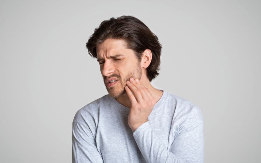 man holding his jaw in pain