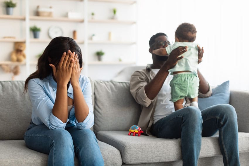 fatigued mom sitting away from husband and child