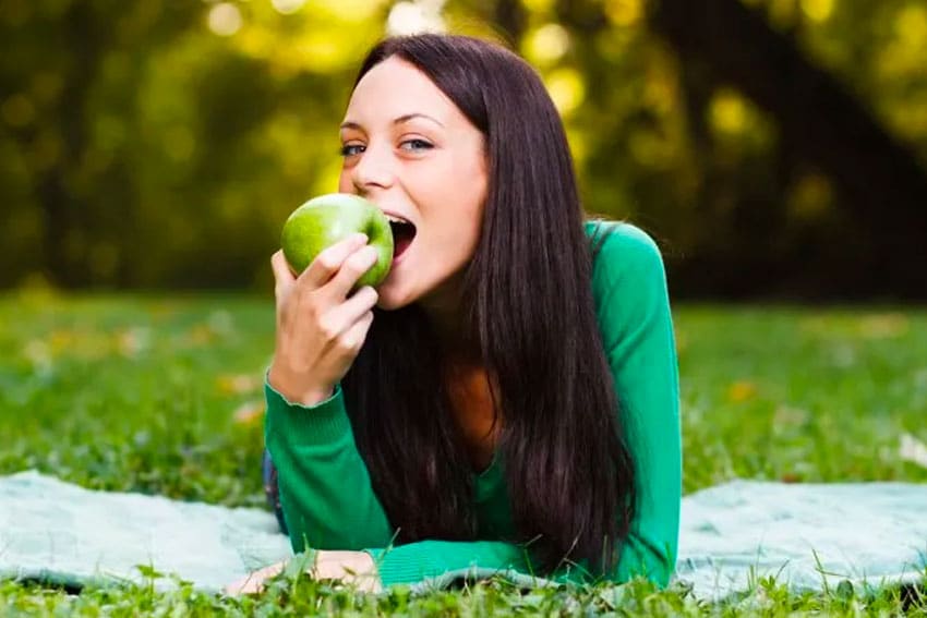 woman eating a bright green apple