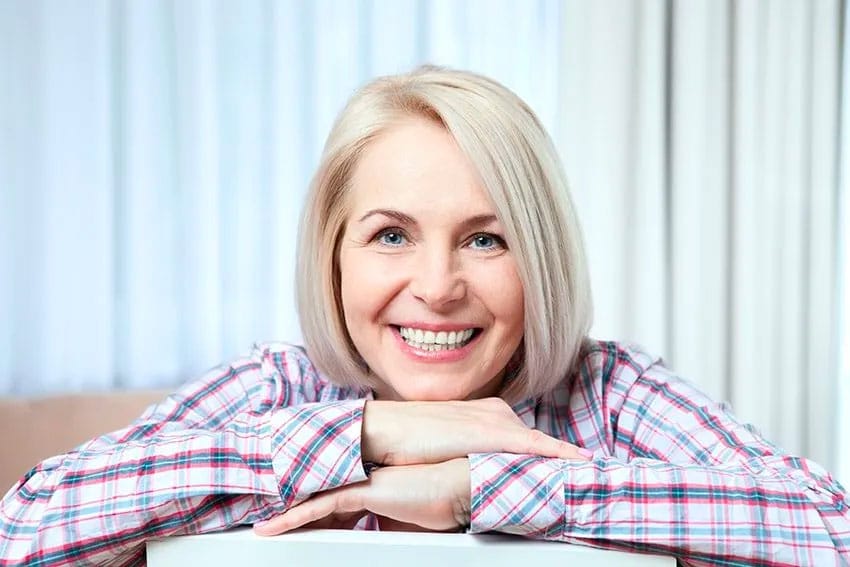 mature woman in flannel shirt shows off her smile