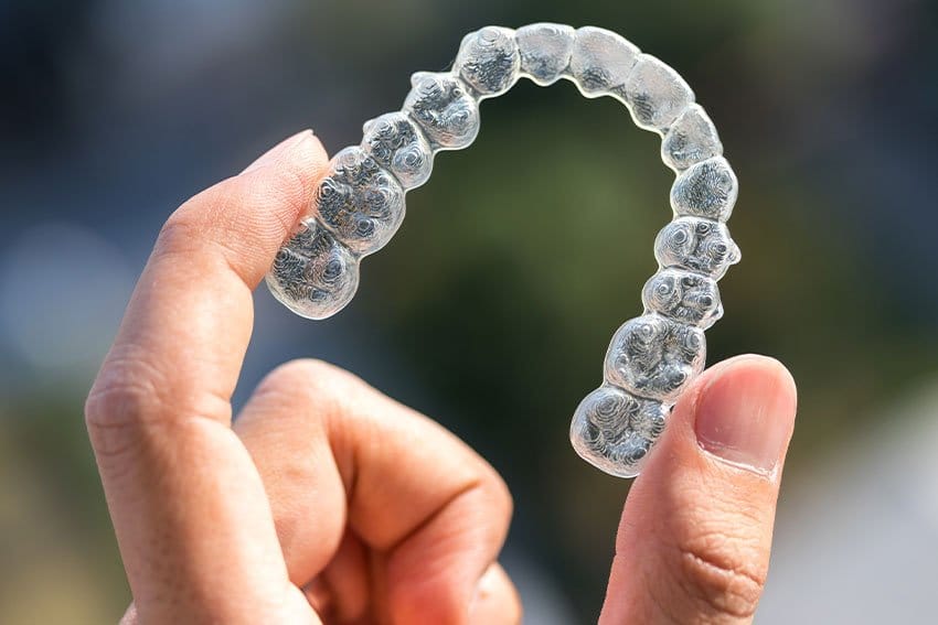 Invisalign clear braces being held in a hand