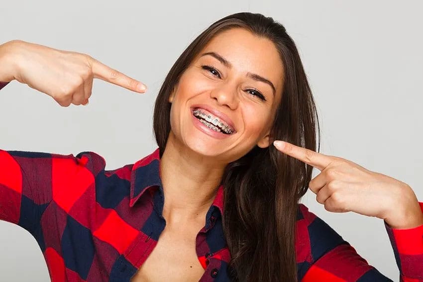 woman pointing to her traditional metal braces