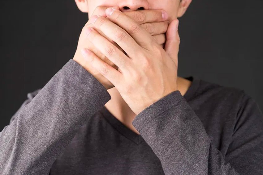 man covering his mouth due to embarrassment