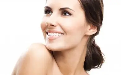 A Woman Smiling with Brown Hair Gum Disease Symptoms