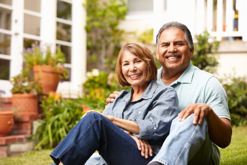 mature couple sitting in the grass embracing and posing for photo