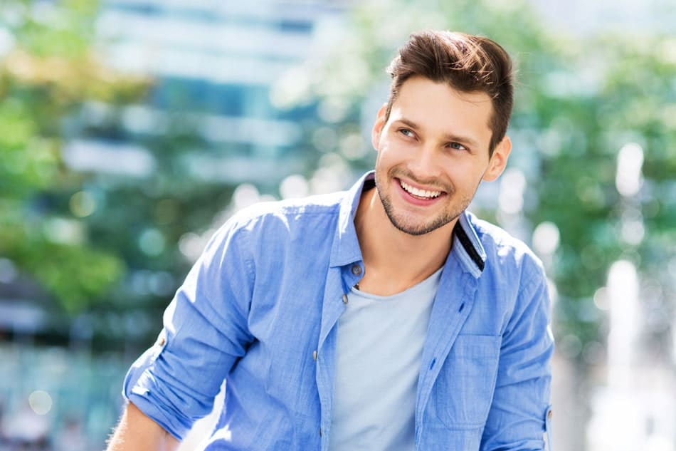 young adult man outside smiling and looking off to the side